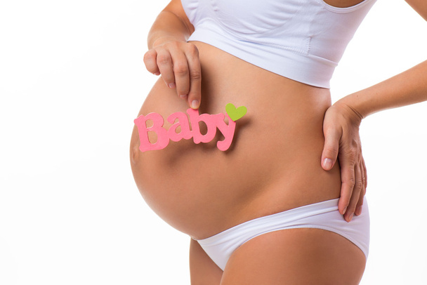 Pregnant belly with pink inscription for baby girl. Pregnant woman waiting a daughter. Close-up horizontal isolated on white background. - Φωτογραφία, εικόνα