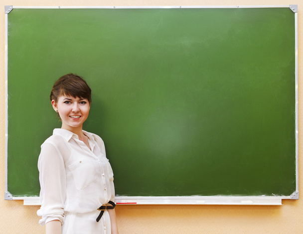 Student girl standing near clean blackboard - Photo, Image