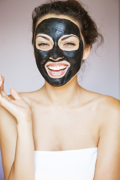 Νεαρή γυναίκα με μια μάσκα για το πρόσωπο του το θεραπευτικό μαύρο mu - Φωτογραφία, εικόνα