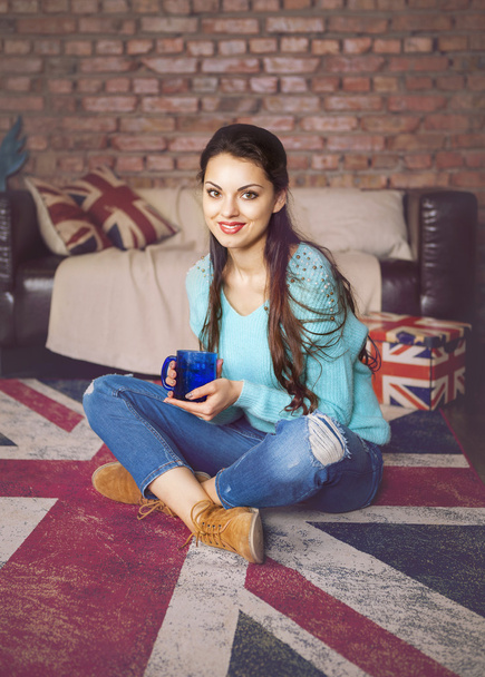 Kaunis hipster tyttö juo teetä lähellä sohvaa
 - Valokuva, kuva