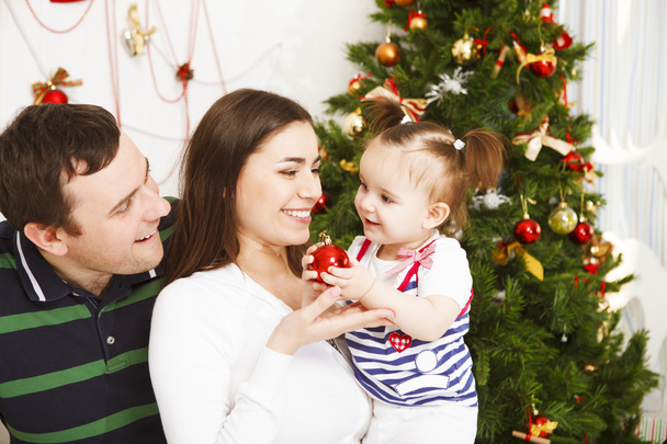 Happy family with Christmas baby near the Christmas tree - 写真・画像