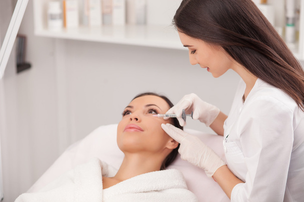 Cheerful young cosmetologist is making botox procedure - Foto, Imagem