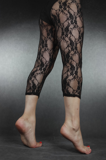Woman legs wearing black lace leggins over grey background - Zdjęcie, obraz