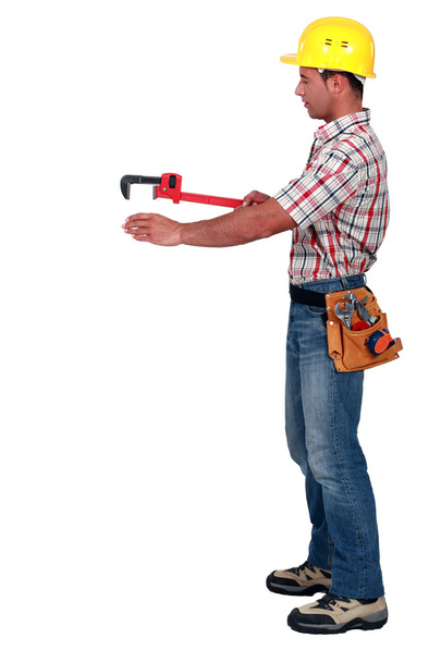 Tradesman using a pipe wrench to help drag and place an object - Photo, image