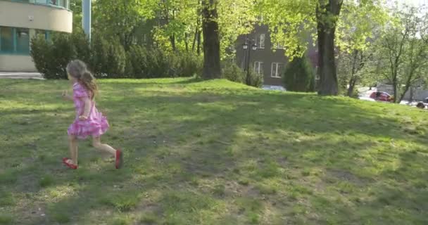 Yeşil taşma payı üzerinde kırmızı ayakkabı pembe elbiseli bebek kız kamera ishal için - Video, Çekim