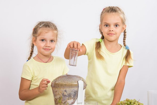 zwei Mädchen, die Fruchtsaft in einer Saftpresse pressen wollen - Foto, Bild