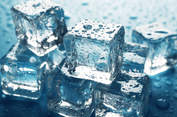 Os cubos de gelo derretendo estão em uma fileira com gotas ao redor, close-up
 - Foto, Imagem