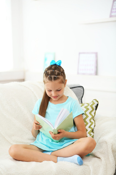 Kis lány ül a kanapén könyv  - Fotó, kép