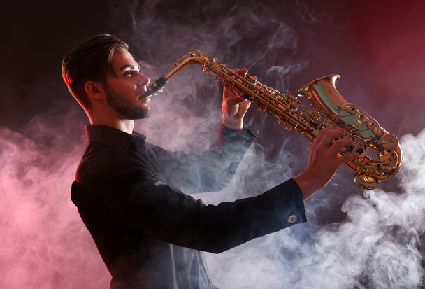 Jovem profissionalmente joga sax na fumaça vermelha
 - Foto, Imagem