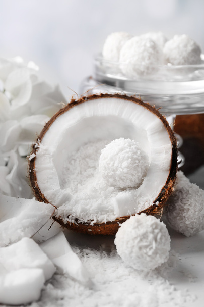 Candies in coconut flakes and fresh coconut on color wooden table, on light background - Φωτογραφία, εικόνα