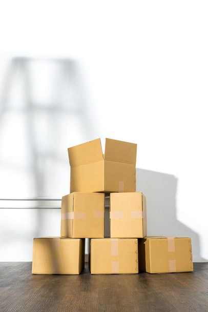 Pile of cardboard boxes on white background with  Ladder shadow - Foto, Imagen