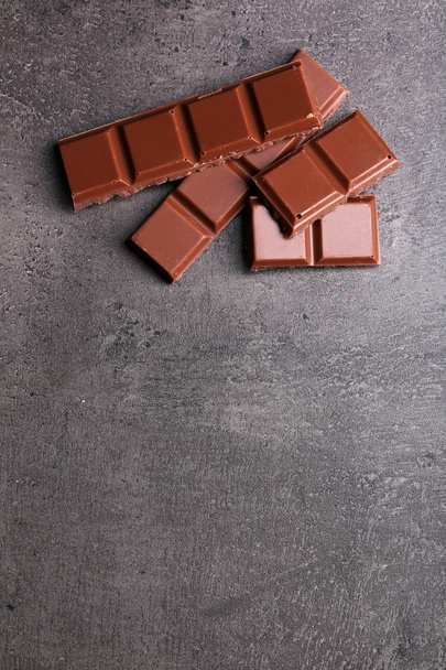 Milk chocolate pieces on gray background - Foto, Imagem