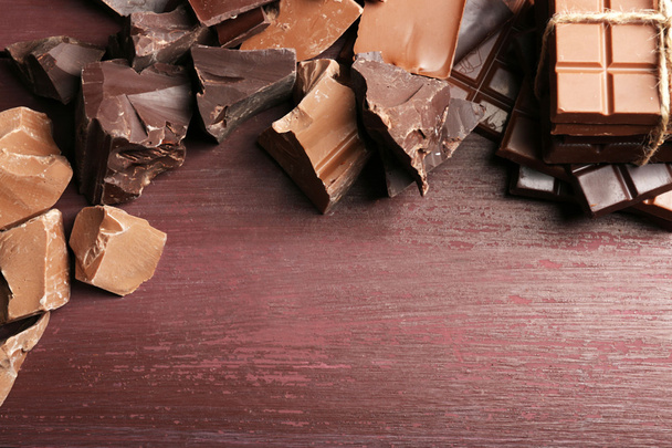 Різноманітність шоколадних шматочків на дерев'яному фоні
 - Фото, зображення
