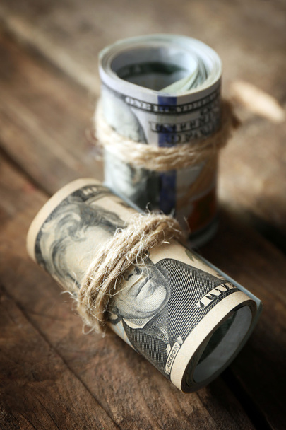 Dollars roll on wooden background - Фото, изображение
