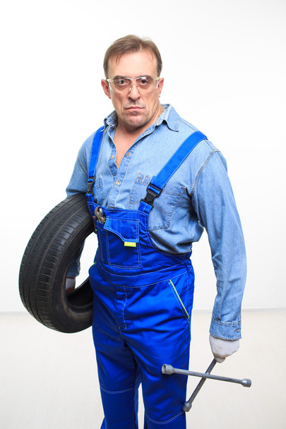 adult male mechanic with a wrench and tire - Fotografie, Obrázek