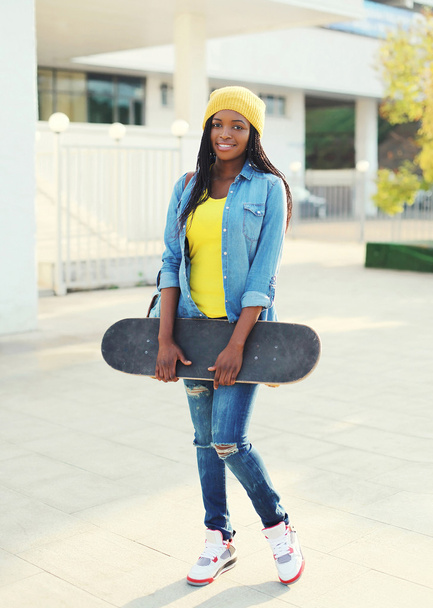 Pretty cool young african woman with skateboard in colorful clot - Zdjęcie, obraz