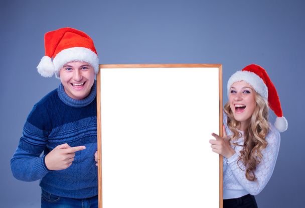 Weihnachtspaar hält weiße Tafel mit leerem Kopierraum - Foto, Bild
