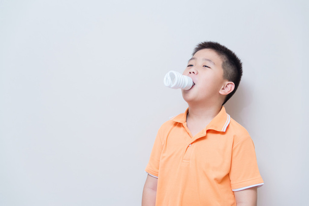 Energy saving lamp in Asian boy mouth - Foto, Bild