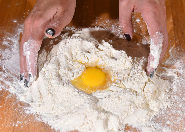 Woman adding egg to the flour - Zdjęcie, obraz
