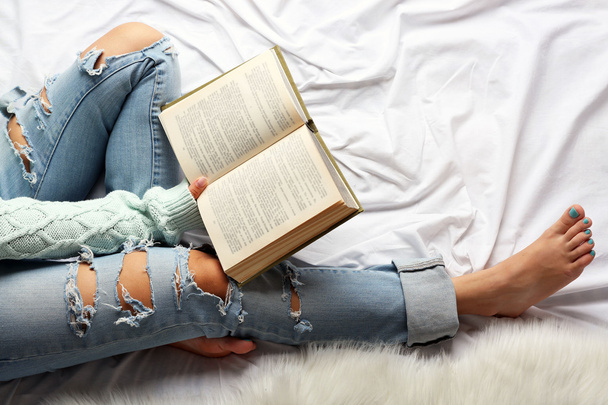 Woman in blue jeans reading book - 写真・画像
