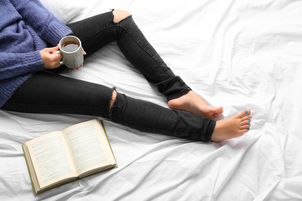 Woman on the bed with old book and cup of coffee, top view point - Foto, Imagem