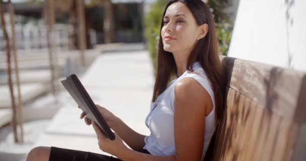 Young businesswoman relaxing on an outdoor bench - Felvétel, videó