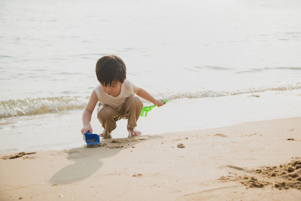 Aasialainen poika leikkii rannalla
 - Valokuva, kuva