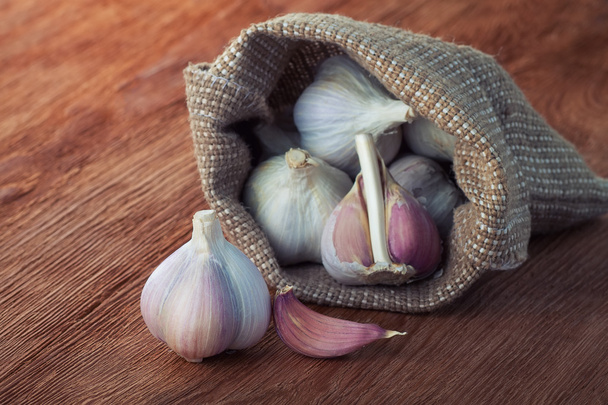 garlics in the bag on a wooden table - Foto, afbeelding
