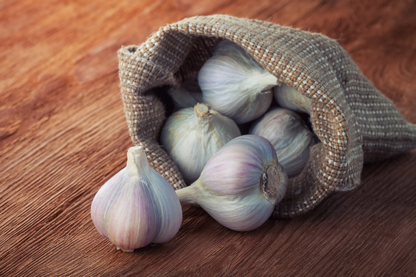 garlic in a bag on wooden table - Фото, изображение