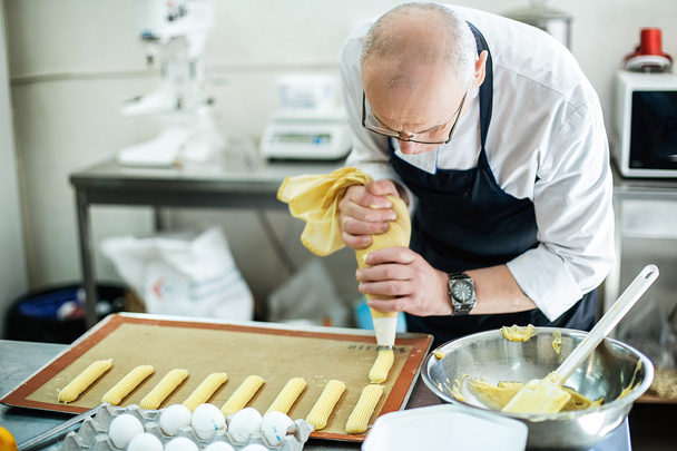 Baker prepares a cake and eclairs - Photo, image
