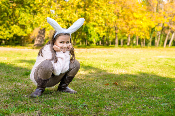 Schattig meisje buiten op de prachtige herfstdag met konijn oren op haar hoofd - Foto, afbeelding