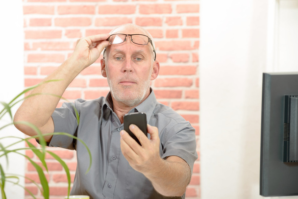 Hombre maduro que tiene problemas para ver la pantalla del teléfono debido a problemas de visión
 - Foto, Imagen