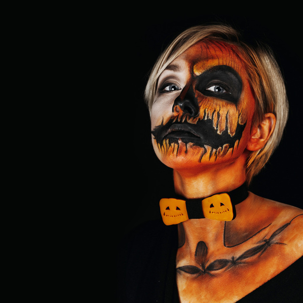 halloween portrait of body art pumpkin girl with pumpkin bowtie on black background. Real greasepaint and face art makeup. Square photo - Foto, imagen
