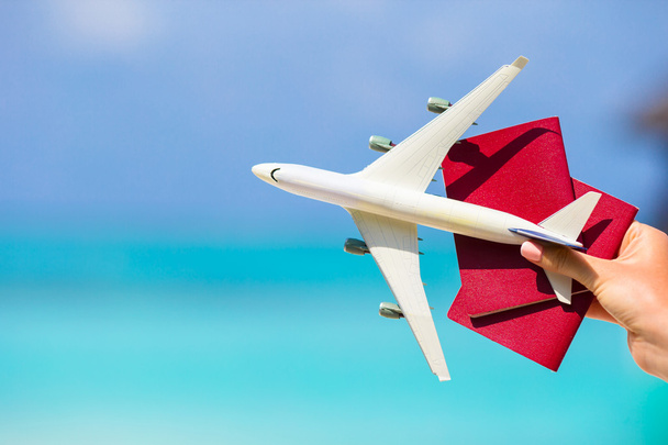 Vértes útlevelek és fehér miniatűr repülőgép hátteret a türkizkék tenger - Fotó, kép