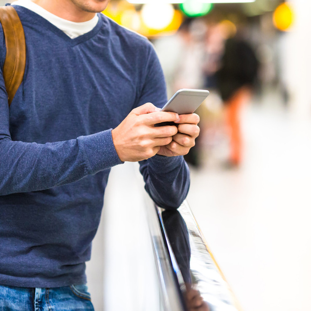 Sırt çantası uçuş bekliyor havaalanında cep telefonu tutan adamla - Fotoğraf, Görsel