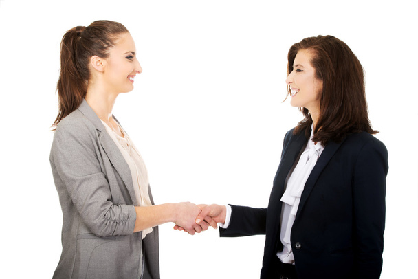 Two women in office outfits giving handshake. - Zdjęcie, obraz