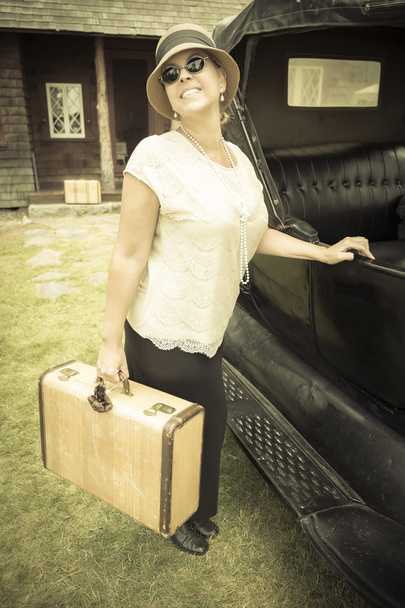 Счастливые 1920-е годы одетая девушка держит чемодан рядом с винтажным автомобилем
 - Фото, изображение