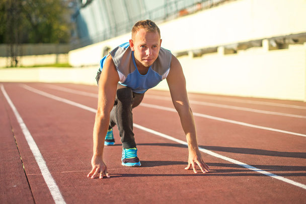 Athletic man standing in  posture ready to run on a treadmill. - Valokuva, kuva