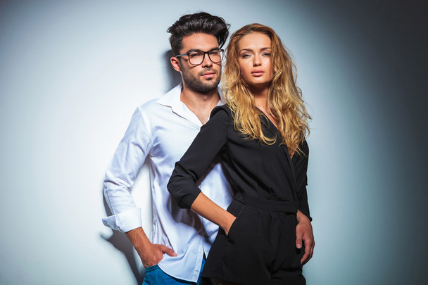 couple pose in studio with hands in pockets while looking at the - Фото, изображение