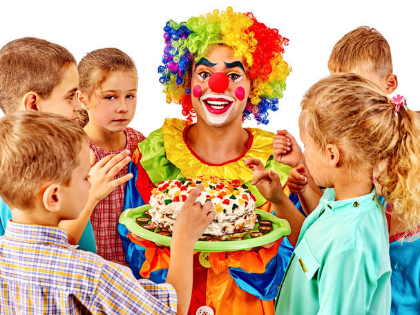 Payaso sosteniendo pastel en cumpleaños con niños en grupo
. - Foto, Imagen