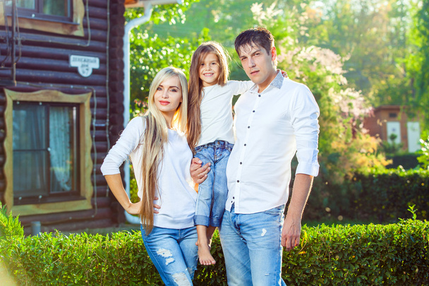 Famille heureuse avec enfant à l'extérieur, sur fond de maison en bois en jeans
 - Photo, image