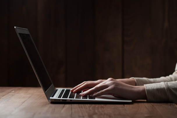 vrouw handen met behulp van laptop op kantoor, met copyspace in donker - Foto, afbeelding