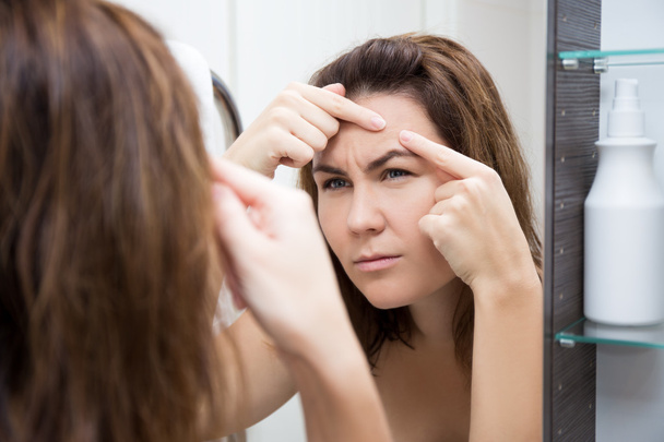 πρόβλημα δέρμα έννοια - θλιβερή γυναίκα κοιτάζοντας καθρέφτη - Φωτογραφία, εικόνα