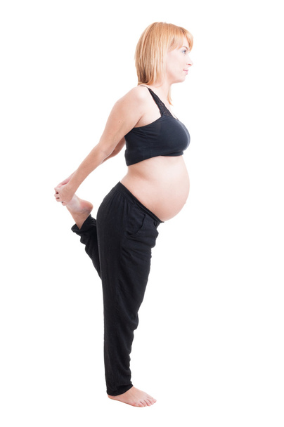 Donna incinta che allunga le gambe in piedi in una gamba
 - Foto, immagini