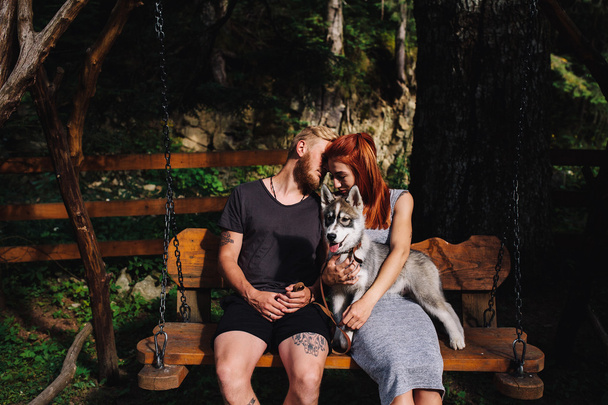 beautiful couple together with dog on a swing - Photo, Image