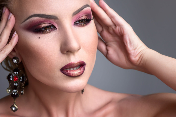 Fashion burgundy makeup look with earrings. Evening makeup, beautiful woman. - 写真・画像