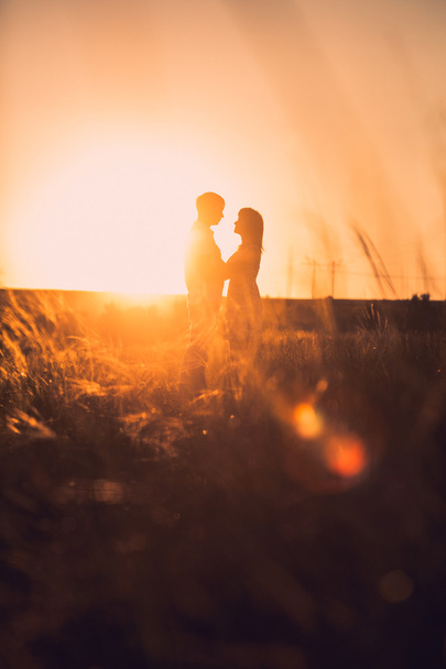 Ρομαντικό ζευγάρι στέκεται και φιλιά για φόντο ηλιοβασίλεμα λιβάδι το καλοκαίρι - Φωτογραφία, εικόνα