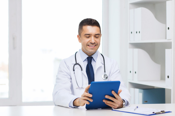 smiling male doctor in white coat with tablet pc - Foto, afbeelding