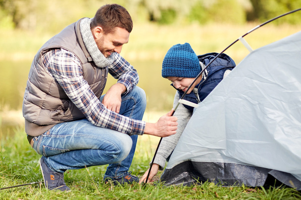 happy father and son setting up tent outdoors - Фото, изображение
