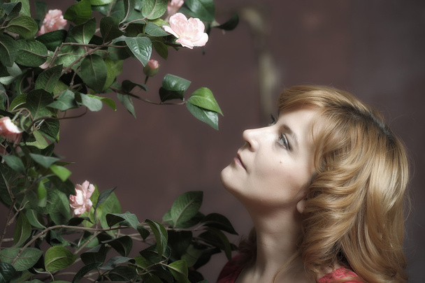 Young woman next to a bush of roses - Valokuva, kuva